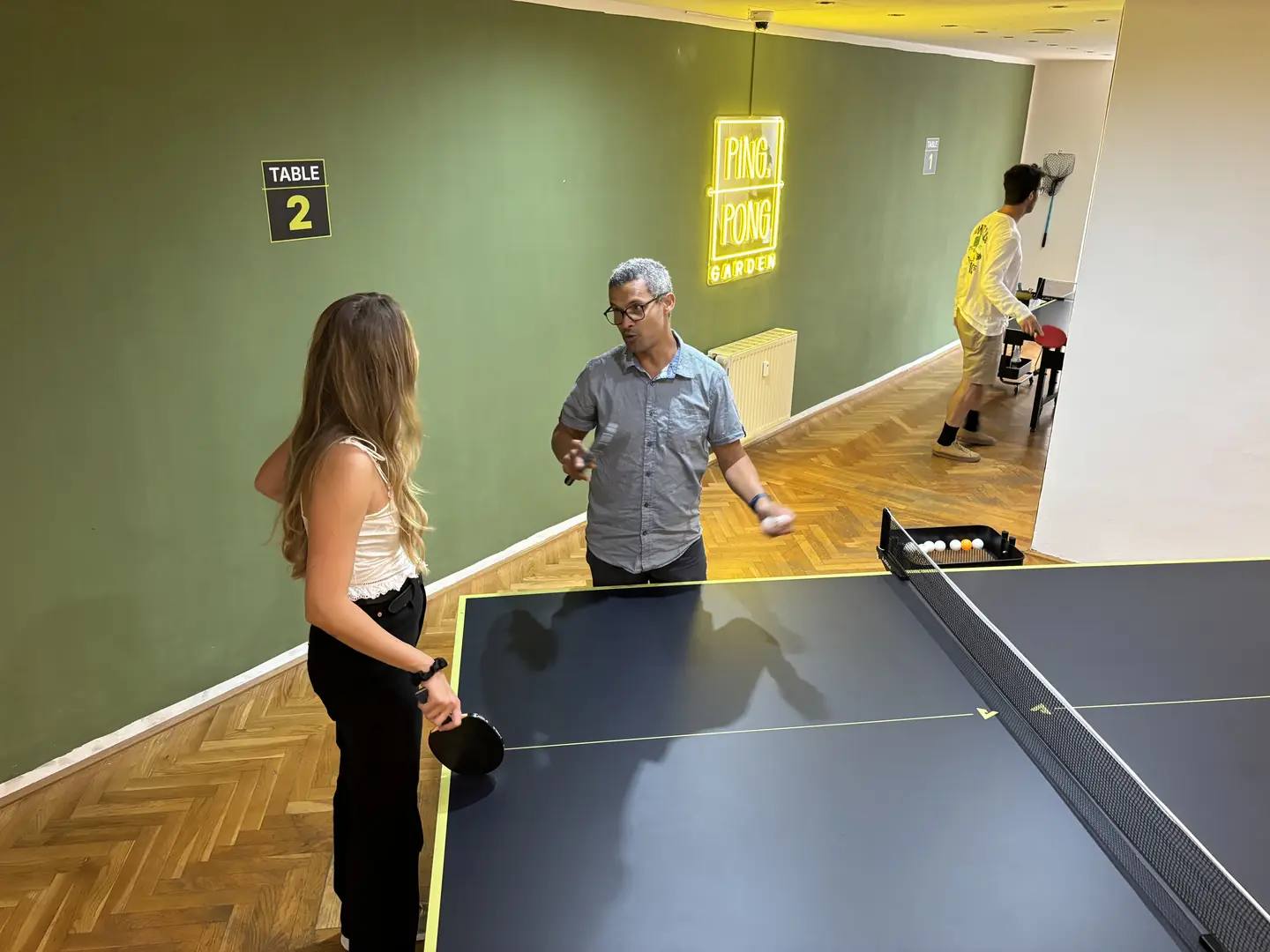 Zwei Spielende im Ballwechsel an Tisch 2 im Indoor-Tischtennisraum in Salzburg