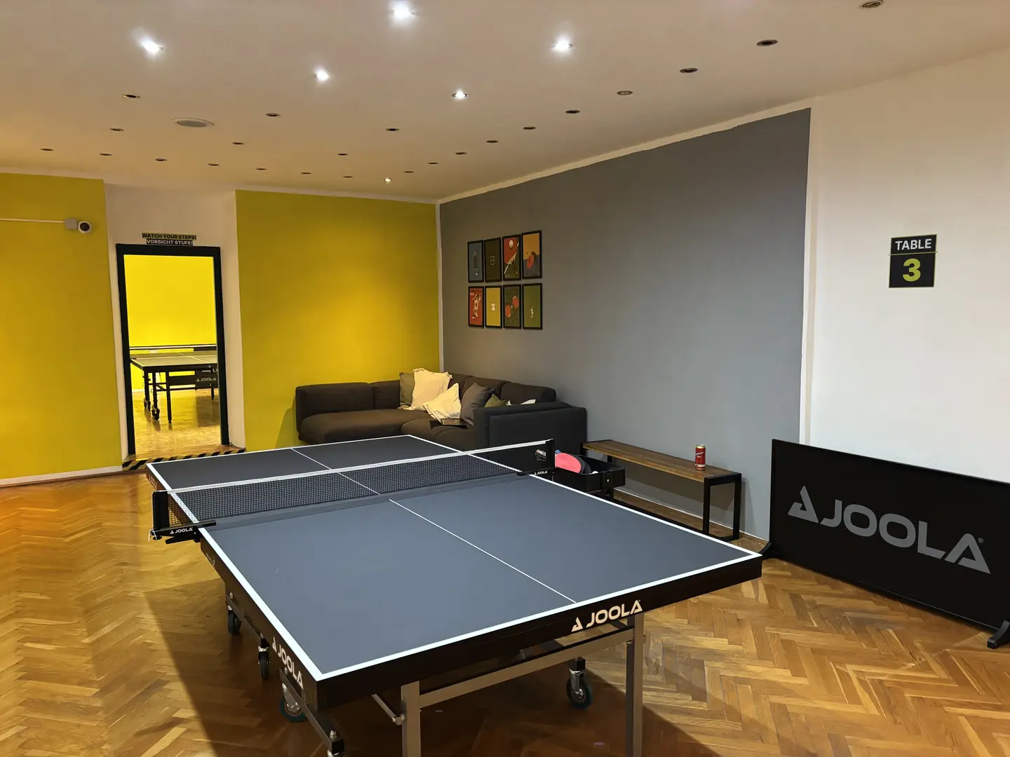 Lounge-Bereich mit Sofa, Bildergalerie und Tischtennisplatte im Ping Pong Garden